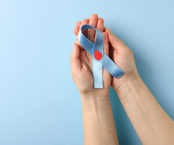 Für ein sicheres Gefühl – heute und in Zukunft Hände halten eine blaue Schleife mit rotem Bluttropfen-Symbol – symbolisiert das Bewusstsein für Diabetes.