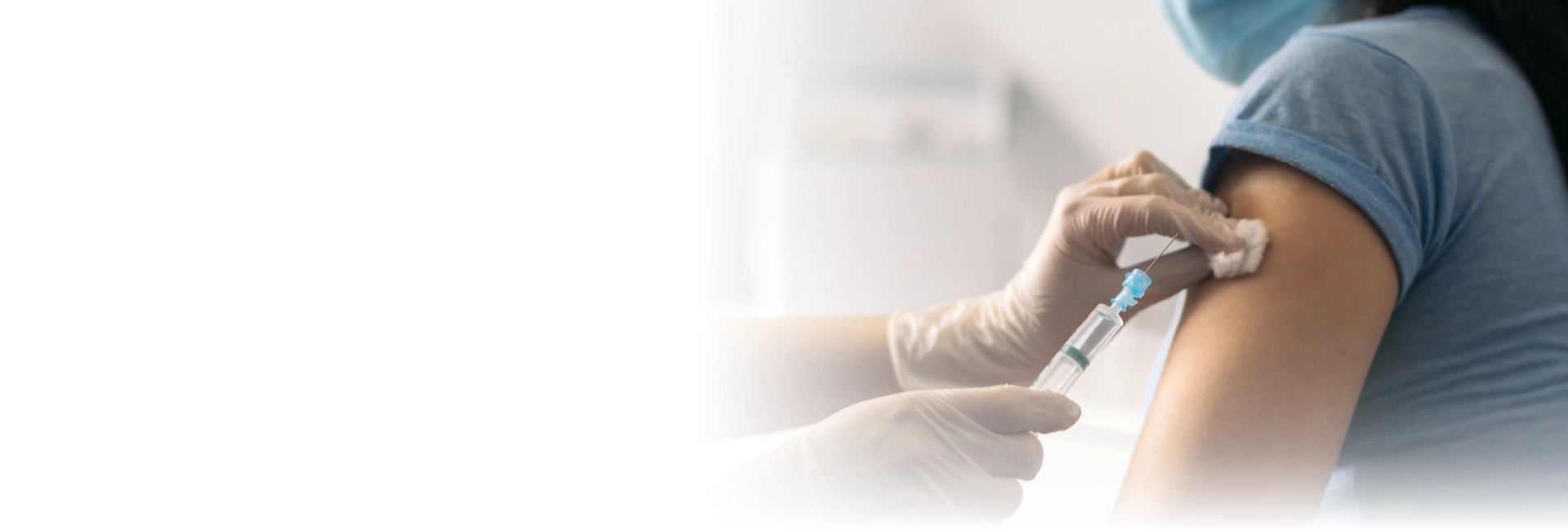 Reisemedizin und Impfungen in Nürnberg Nahaufnahme einer medizinischen Fachkraft, die einer Person im blauen T-Shirt eine Injektion in den Oberarm verabreicht – symbolisiert Impfung oder medizinische Vorsorgemaßnahme in der Arztpraxis.