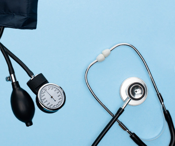 Untersuchung Blutdruckmessgerät und Stethoskop auf hellblauem Hintergrund – steht für medizinische Vorsorge und Diagnostik.