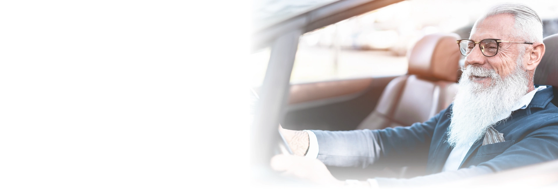 Verkehrsmedizinische Untersuchung in Nürnberg und Umgebung Älterer Mann mit weißem Bart fährt entspannt ein Auto, im eleganten Outfit und bei hellem Licht – symbolisiert Fahrtauglichkeitsuntersuchung und sicheres Autofahren im Alter.