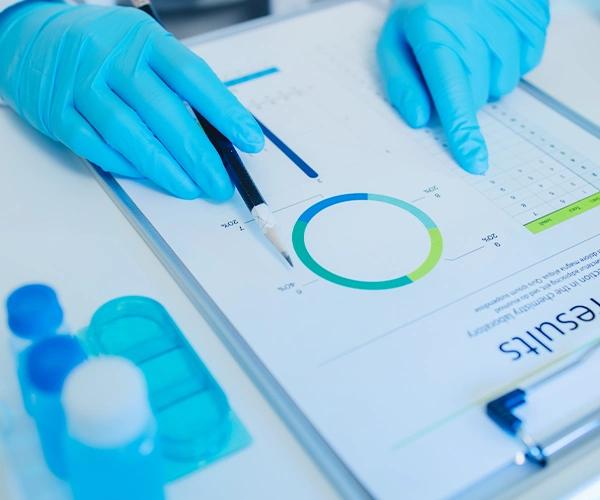 Nahaufnahme von medizinischem Fachpersonal mit blauen Einweghandschuhen, das Analyseberichte mit Diagrammen und Messwerten zur Diagnostik und Therapieplanung auswertet.